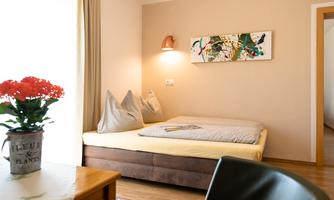 A cozy room with a bed and modern decor. On the table, there is a pot with a plant.