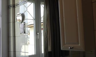 A modern bathroom with a double sink and large mirrors. Soft light filters into the room through the window.
