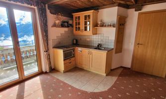 A cozy kitchen with wooden details and windows that offer a view of the sky. The room is bright and inviting, with a warm hue.