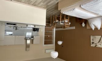 A modern room with a double bed and a kitchenette. The space is bright and friendly, with a table and chairs for meals.