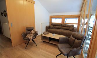 A modern living room with a comfortable sofa and two chairs. Large windows provide plenty of daylight and a cozy atmosphere.