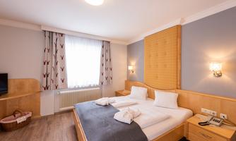 A modern bedroom with a large bed and two pillows. The walls are painted light and the room has plenty of natural light.