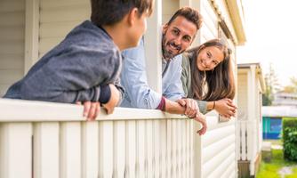 A family is standing on the porch and smiling. They are enjoying their time together outdoors.
