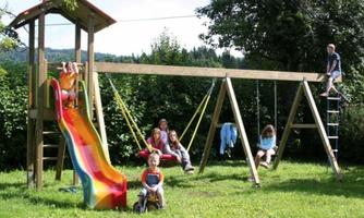 A colorful playground with a slide, swings, and a climbing frame. Children are playing and having a lot of fun outdoors.