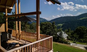 A beautiful balcony overlooking a green landscape and mountains in the background. The sun is shining and the clouds are loosely scattered in the sky.