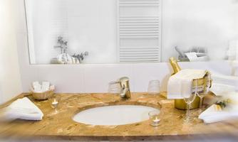 An elegant bathroom with a marble sink and luxurious accessories. Glasses and a champagne cooler add a festive touch to the space.