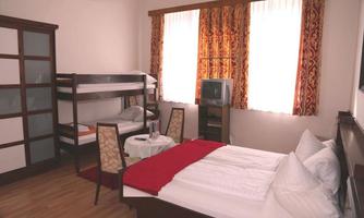 A simple room with a double bed and a bunk bed.  
Large windows let in plenty of light and there is a small table with chairs.