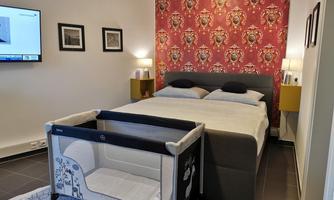 A modern bedroom with a double bed and a children's bed. The walls are decorated with a striking pattern and a television is visible.