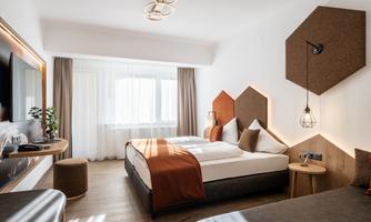 A modern hotel room with two beds and an elegant design. Large windows provide plenty of daylight and a cozy atmosphere.