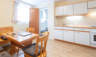 A bright kitchen with a dining table and chairs. The walls are painted in soft colors and there is plenty of daylight.