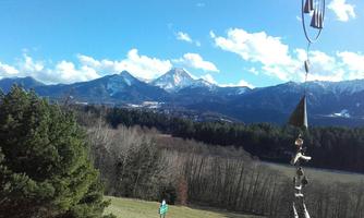 A breathtaking mountain landscape with snow-covered peaks and clear blue sky. In the foreground, there are trees and a meadow.