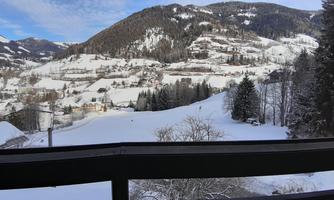 A beautiful winter landscape with snow-covered mountains and trees. The clear sky is blue and radiant.