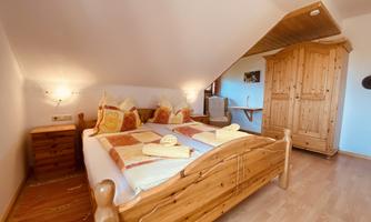 A cozy bedroom with a wooden bed and rustic furniture piece. The soft lighting creates a relaxed atmosphere.