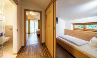 A cozy bathroom and a bedroom with hardwood floors and large windows. The room is bright and inviting.