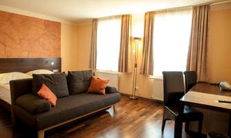 A modern room with a comfortable sofa and a dining table. Large windows provide plenty of light and a cozy atmosphere.