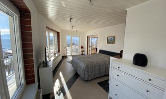 A bright bedroom with a large bed and a modern wardrobe. The windows offer a beautiful view of the countryside.
