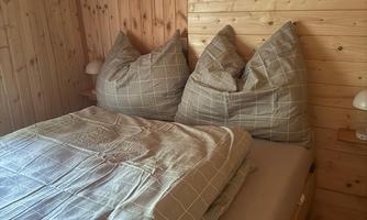 A cozy bedroom with wood paneling and a double bed. The pillows are large and plush, perfect for relaxing.