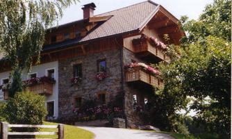 A charming country house with wooden cladding and flower balconies. It is located picturesque in a green environment.