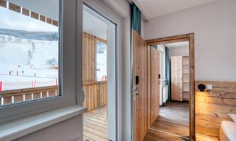 A cozy room with access to a balcony. Outside, you can see snow and ski slopes.