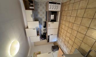A modern kitchen with bright furniture and a spacious work surface. The floor is tiled with matching tiles and the walls are tastefully designed.