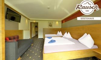A cozy guest room with two beds and modern furniture. The room includes a television and a seating area.