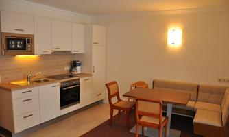 A modern kitchen with a dining area. The furniture is in light colors, and the atmosphere is friendly and inviting.