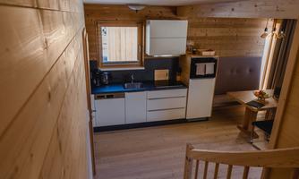 A modern kitchen with wooden paneling and a large window. There is a dining table and chairs that create a cozy atmosphere.