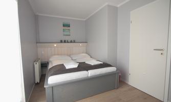 A cozy bedroom with a large bed and neutral colors. The relaxing atmosphere is complemented by the minimalist decor.