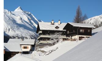 A picturesque winter village with snow-covered hills and mountains in the background. The traditional houses radiate coziness.