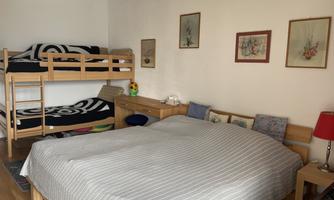 In the bedroom, there is a double bed, a bunk bed, a wardrobe, and a small desk with direct access to the balcony.