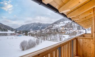 A beautiful view from a balcony of a snowy landscape. The surrounding mountains and the village are picturesque and inviting.