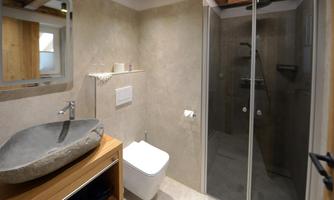 A modern bathroom with an elegant shower and a striking sink. The walls are in neutral tones, and there are wooden details.