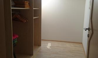 A bright room with an open wardrobe and shelves. Light pours in through a window, creating a friendly atmosphere.