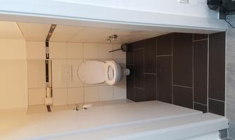 A small, clean bathroom with a toilet. The floor is tiled with dark gray tiles.