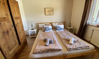 A cozy bedroom with a double bed and soft blankets. In addition, there is a large wooden wardrobe and a windowsill with natural light.
