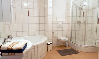 A modern bathroom with a bathtub and a shower. The walls are covered with white tiles, and there are towels right next to the sink.