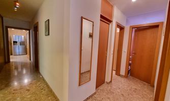 A bright hallway with several doors and a mirror. The floor is tiled with gray marble.