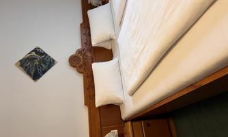 A cozy bedroom with a large double bed and two nightstands. A decorative artwork hangs on the wall.