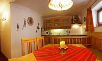 A cozy kitchenette with wooden shelves and a dining table. The table is decorated with a red tablecloth and a candle.