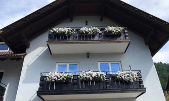 A modern house with two balconies. The balconies are adorned with white flowers.