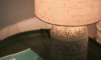 A decorative lamp stands on a green tray next to a book titled "Your Region." The lamp has a warm shade and an appealing design.