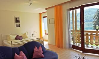 A cozy room with a bed and a blue sofa.  
Large windows provide a beautiful view of the nature outside.