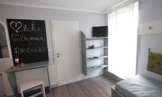 A cozy room with bright walls and a large window. On the wall, there is a blackboard with a welcome message.