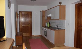 A bright and modern kitchen with wooden cabinets and a small dining area. The space is well-furnished and offers plenty of natural light.