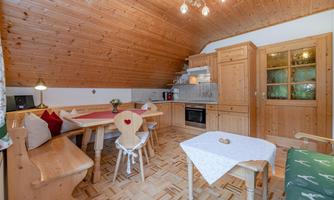 A cozy kitchen with wooden paneling and a dining table. The decor is rustic and inviting.