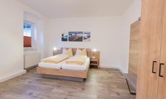 A modern room with a double bed and wood decor. The walls are bright and the room is simply but invitingly designed.