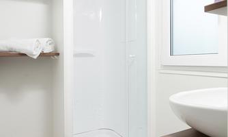 A modern bathroom with a clear shower cubicle and a sink. An orchid and fresh towels give the room an inviting atmosphere.