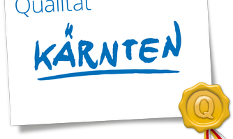 A quality seal with the inscription "Kärnten" in blue letters. The symbol features a golden medal with a "Q".