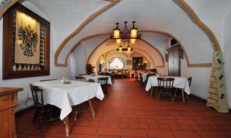 A cozy restaurant with a vaulted ceiling area.  
The tables are set with white tablecloths, and warm lighting creates an inviting atmosphere.