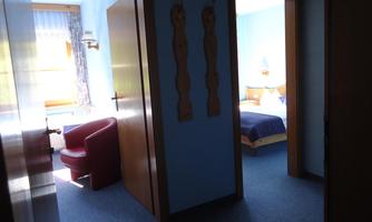 A bright room with blue walls and a red armchair. You can see another bedroom in the background.